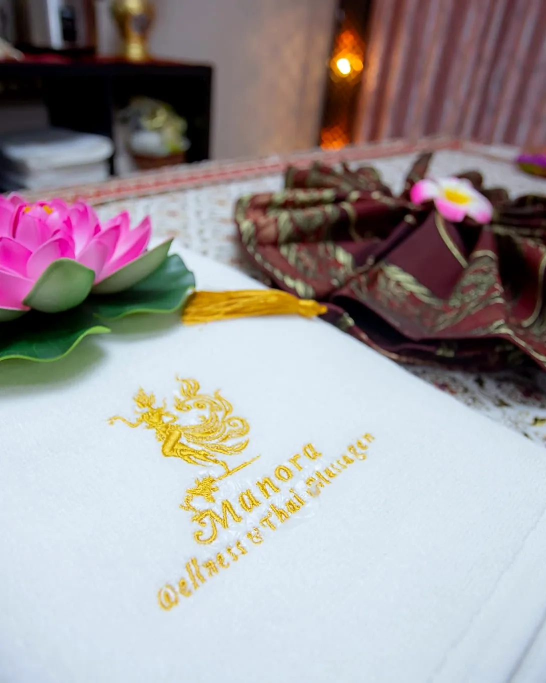 Gefaltetes Manora Tuch mit Lotusblüte auf der Massageliege